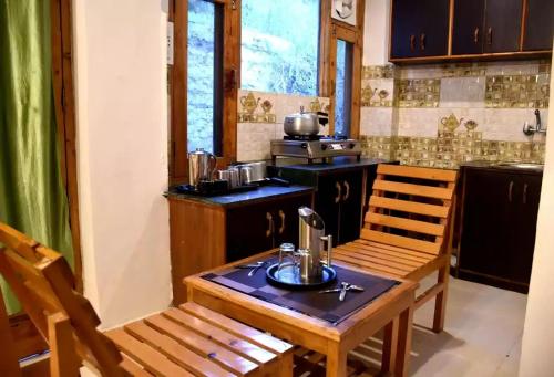 eine Küche mit einem Holztisch und 2 Stühlen in der Unterkunft Koushalya Homes in Vashisht