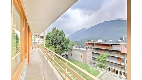 einen Balkon mit Blick auf ein Gebäude und die Berge in der Unterkunft Koushalya Homes in Vashisht