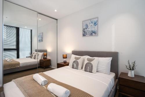 a bedroom with two beds and a mirror at Light Filled 2br Southbank Parking Pool in Melbourne