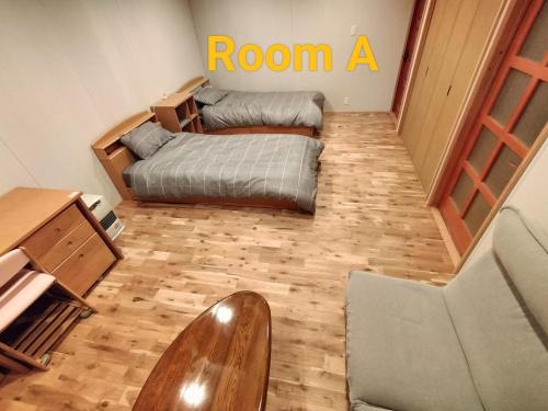 een kamer met 2 bedden, een bureau en een stoel bij Long Stay Takayama in Takayama