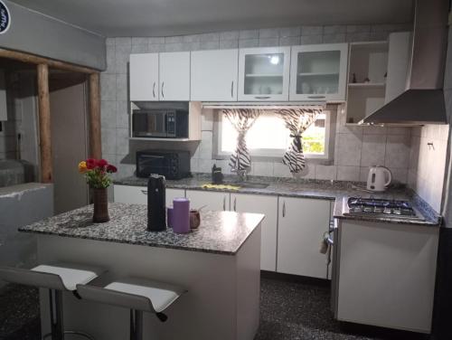 a kitchen with white cabinets and a counter top at Hermosa casa para vacaciones in Guaymallen