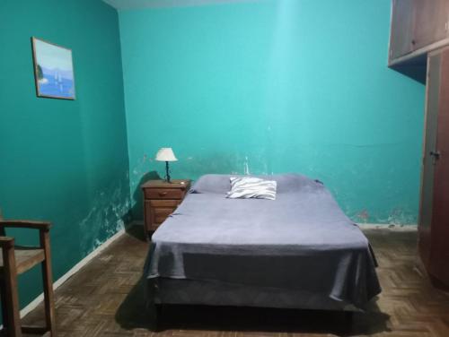 a bed in a room with a blue wall at Hermosa casa para vacaciones in Guaymallen