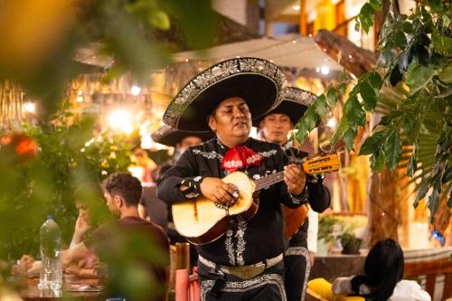 a man wearing a hat playing a guitar at Banana's Adventure Hostel in Ica