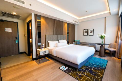 a bedroom with a white bed and a living room at Deka Hotel Surabaya HR Muhammad in Surabaya