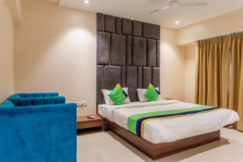 a bedroom with a large bed and a blue chair at Treebo Blossom - Viman Nagar in Pune