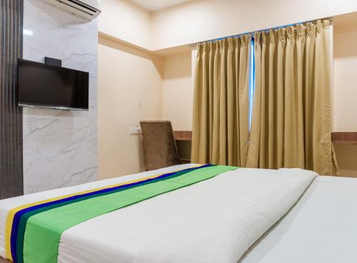 a bedroom with a bed and a flat screen tv at Treebo Blossom - Viman Nagar in Pune