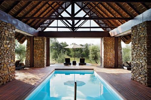 uma piscina numa casa com um pátio em Shambala Private Game Reserve em Vaalwater