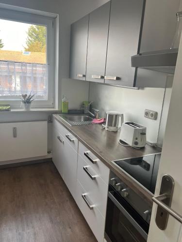 a kitchen with white cabinets and a window at Ferienwohnung Niedermoosen in Riedering