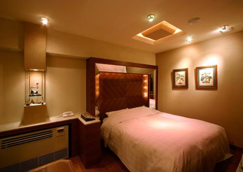 a bedroom with a bed and a dresser with a mirror at HOTEL ｍ in Matsudo