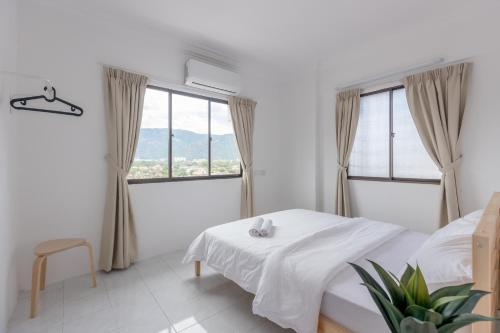 a white bedroom with a bed and two windows at The Eastern, by Meixi in Jelutong