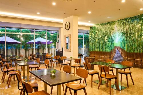 ein Restaurant mit Tischen und Stühlen und einem großen Wandbild in der Unterkunft Grand Orchid Hotel Yogyakarta in Yogyakarta