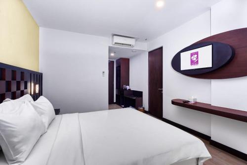 日惹的住宿－日惹大蘭花酒店，卧室配有白色的床和墙上的电视。