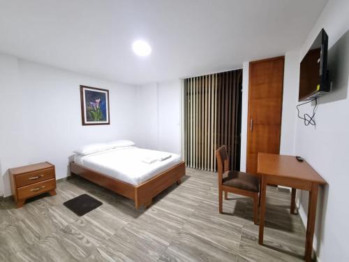 a hotel room with a bed and a desk and a desk at Hotel San Marcos Las Lajas in Ipiales