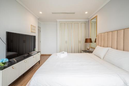 1 dormitorio con 1 cama blanca grande y TV en Vera Saigon Apartments - Vinhomes Central Park, en Ho Chi Minh