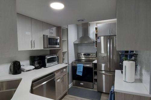 a kitchen with stainless steel appliances and cabinets at Cozy 2-Bedroom Basement Guest Suite with Private Entrance and Proximity to the Airport in Edmonton