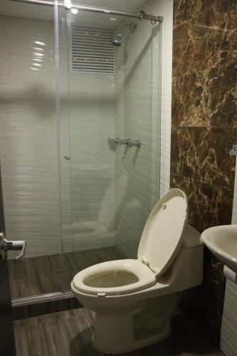 a bathroom with a toilet and a glass shower at Hotel San Marcos Las Lajas in Ipiales
