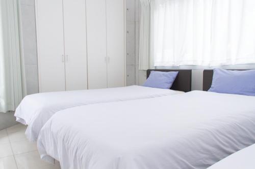 2 Betten in einem Schlafzimmer mit weißer Bettwäsche und blauen Kissen in der Unterkunft Shiraho Villa - Vacation STAY 13688v in Ishigaki-jima