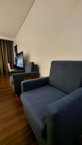 a living room with two blue couches and a television at Mountain View,Room 549 Private Unit at The Forest Lodge,Camp John Hay Suites in Baguio