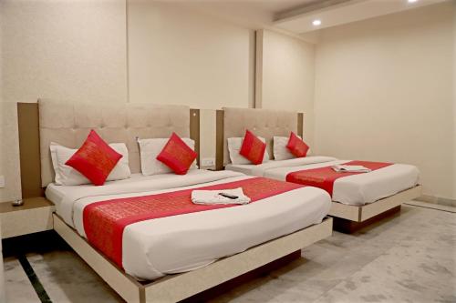 two beds with red pillows in a room at Hotel Klick International in New Delhi