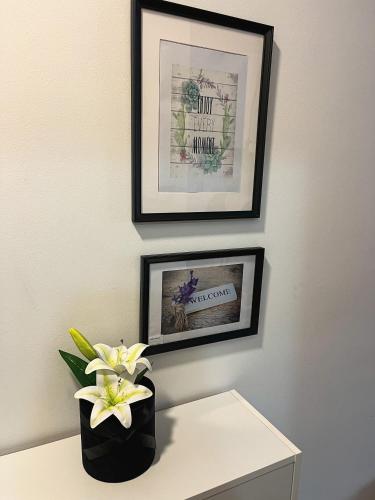 a vase of flowers on a table with two pictures at Apartman Malena in Trebinje