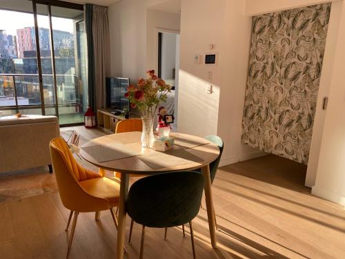 a dining room table with chairs and a vase of flowers at Darling Harbour 2b apt Car space upon request ICC CBD family friendly with view in Sydney
