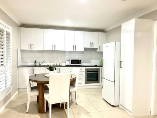a kitchen with a table and a white refrigerator at Guest house in Harrington Park in Narellan