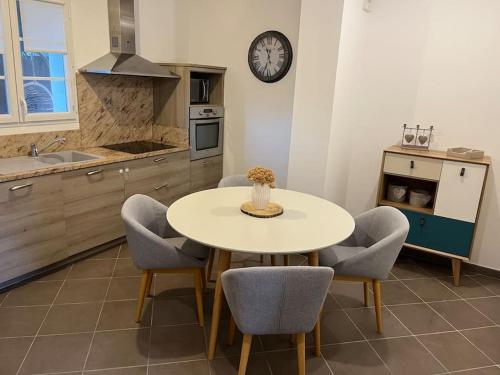 une cuisine avec une table et des chaises et une horloge au mur dans l'établissement Maison avec jardin, à Patrimonio