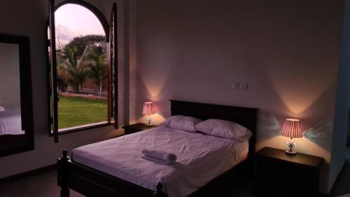a bedroom with a bed with two lamps and a window at Jardines de Milé in Laredo Hacienda