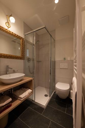 a bathroom with a shower and a toilet and a sink at Pension Apartments Klotznerhof in Schenna