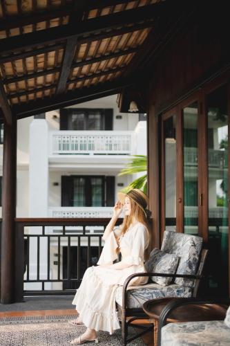 a woman in a white dress sitting on a bench at Buri Sriping Riverside Resort & Spa in Chiang Mai