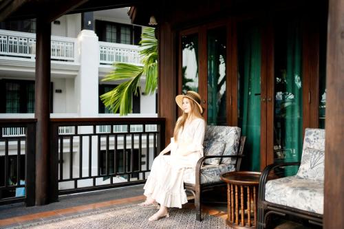 a woman in a white dress sitting on a chair at Buri Sriping Riverside Resort & Spa in Chiang Mai