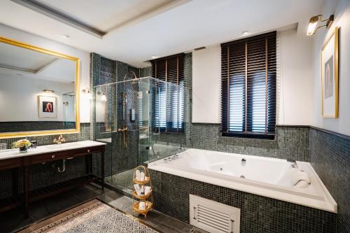 a bathroom with a tub and a glass shower at Buri Sriping Riverside Resort & Spa in Chiang Mai
