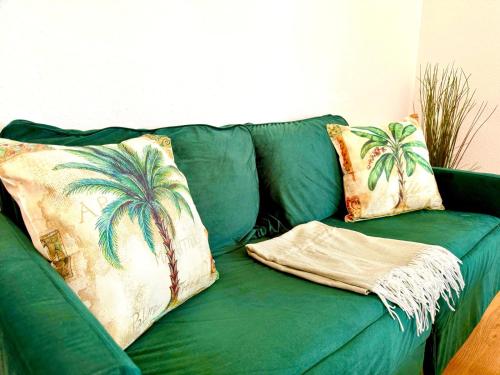 a green couch with two palm trees pillows on it at Zuhause im Ruhrgebiet 4 mit Balkon in Oberhausen