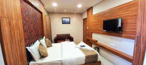 een hotelkamer met een bed en een flatscreen-tv bij The Parion Business Class Hotel in Chennai