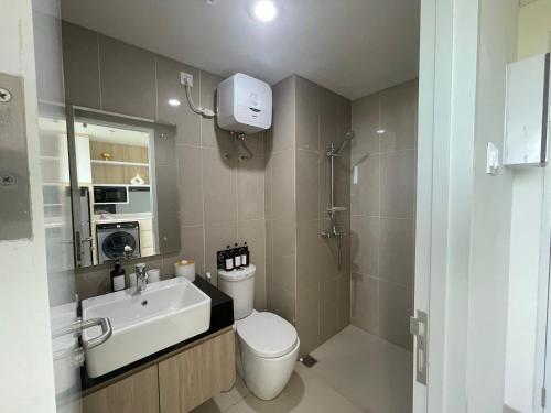 a bathroom with a toilet and a sink and a mirror at Sea View Apartment at Nuvasa Bay Kalani Tower in Nongsa Area in Telukmataikan