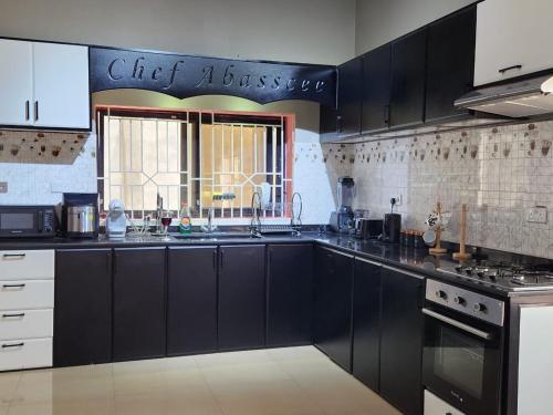 a large kitchen with black cabinets and a window at Prestigious Elegant Duplex - Abasscee in Freetown
