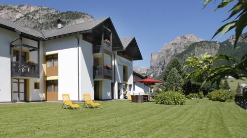 two chairs on a lawn in front of a building at Residence Villa al Sole in Selva di Val Gardena