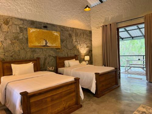 1 Schlafzimmer mit 2 Betten und einer Steinmauer in der Unterkunft Arsulana Eco Lodge & Spa in Ginigathena