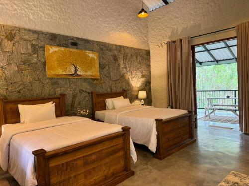 a bedroom with two beds and a stone wall at Arsulana Eco Lodge & Spa in Ginigathena