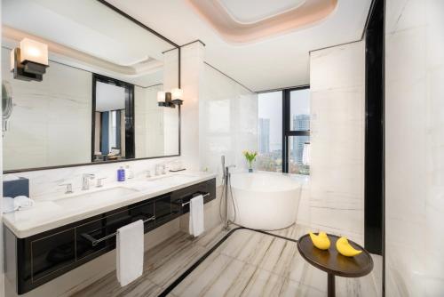 a white bathroom with a tub and a sink at voco - Hangzhou Binjiang Minghao, an IHG Hotel in Hangzhou