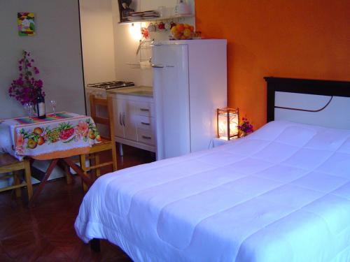 a bedroom with a large white bed and a kitchen at chales azaleia todos in São Bento do Sapucaí