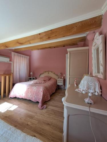 - une chambre rose avec un grand lit et une table dans l'établissement Location en Corse au pied du Monte Cintu, à Lozzi