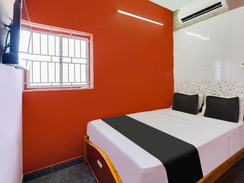 a bedroom with a bed with an orange wall at Collection O AVR ROOMS in Chennai