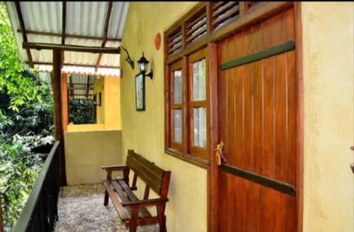 a house with a wooden door and a bench at dulma sinharaja resot in Nelluwa