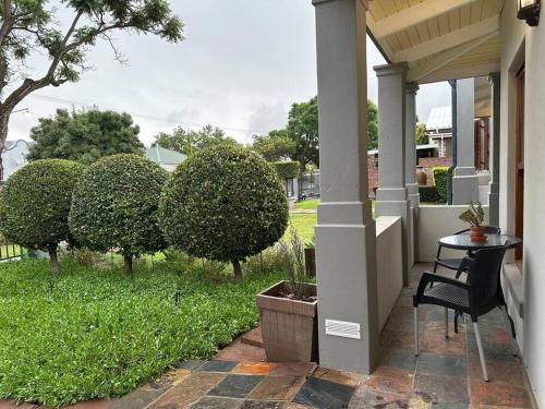 a porch with a black chair and a table and bushes at Piekfijn Robertson in Robertson