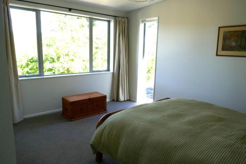 um quarto com uma cama e uma grande janela em The Tree house em Paraparaumu