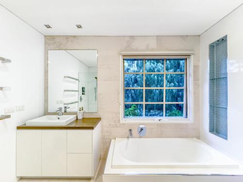 baño con bañera grande y ventana en Pride Leisure Tudor House en Park Orchards