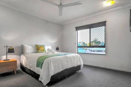 a white bedroom with a bed and a window at An abode on Abbott - In the heart of the city in Cairns