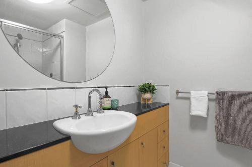 a bathroom with a white sink and a mirror at An abode on Abbott - In the heart of the city in Cairns