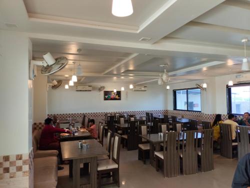 un comedor con mesas y sillas y gente comiendo en Hotel Amidhara, en Dwarka